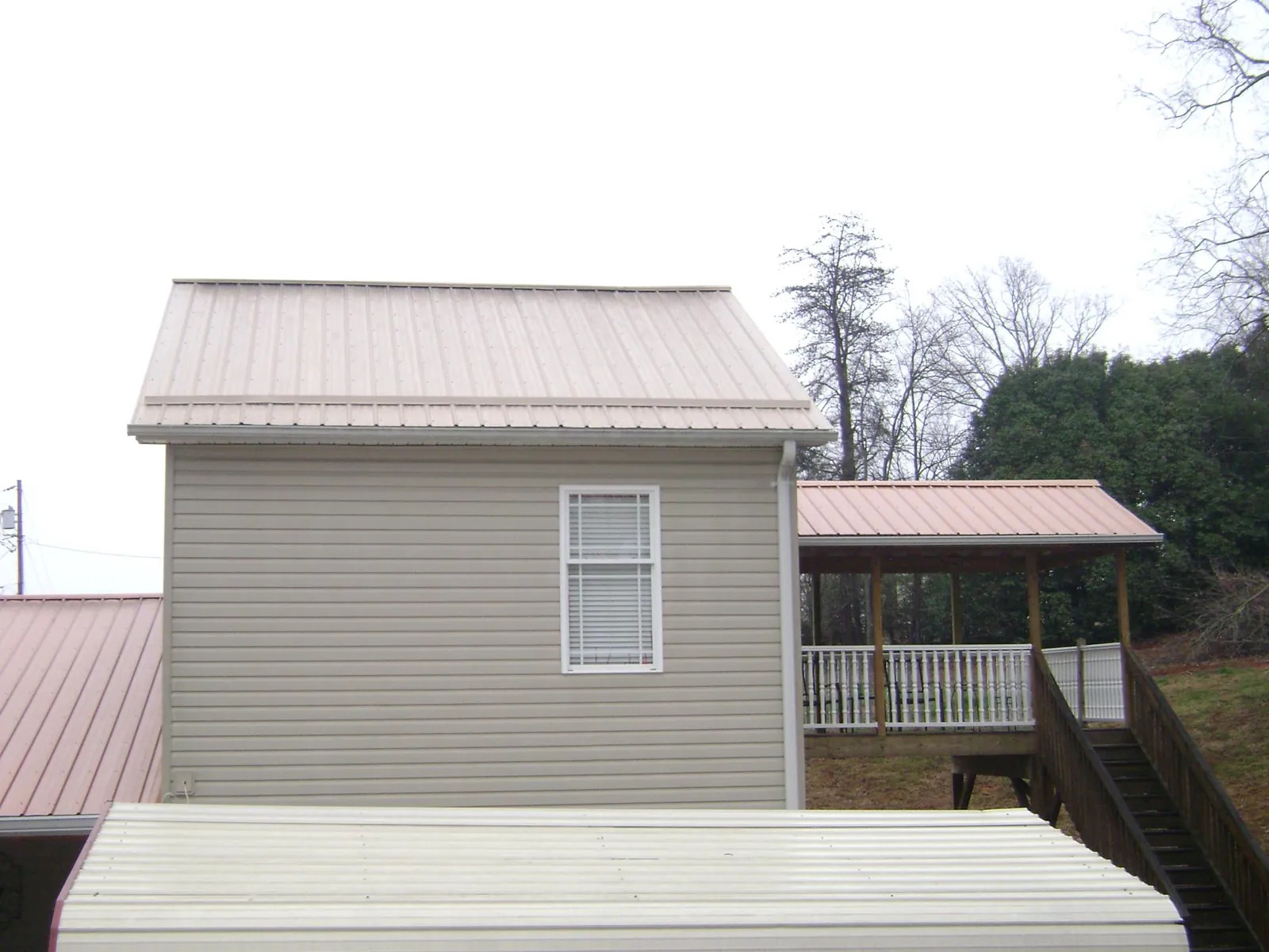 Tan metal roofs on a two story addition and attached porch, from a Roof Replacement job in Flagler Beach
