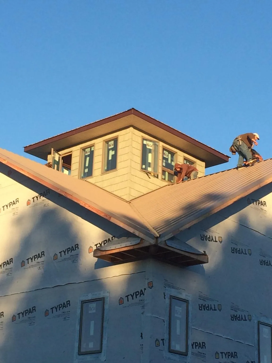 Roofers working around a rooftop cupola on a new metal roof at sunset — Roof Waterproofing in Flagler Beach by Roofing Brothers
